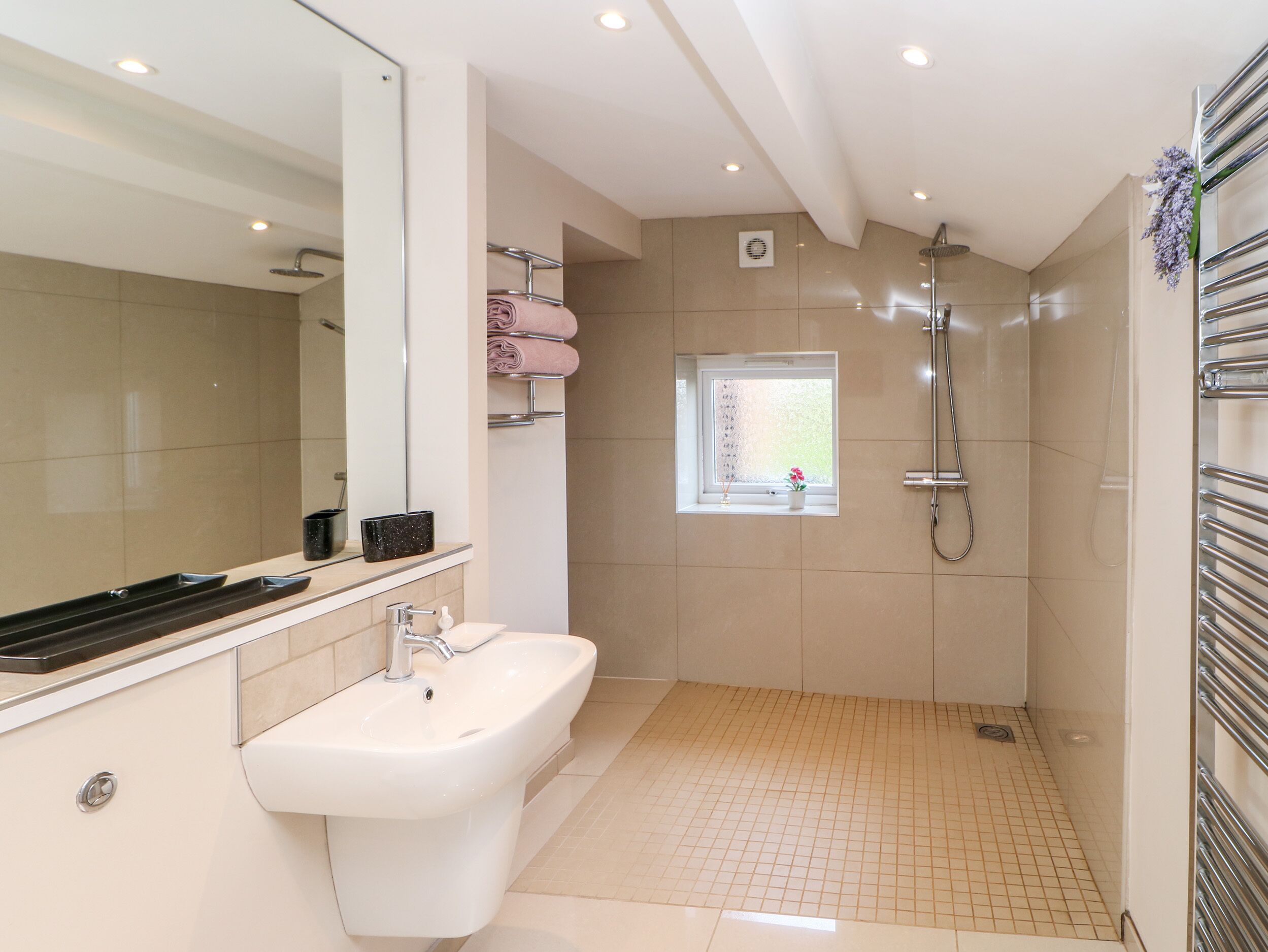 Ein modernes Badezimmer mit großem Spiegel, Waschbecken, Dusche und Fenster.