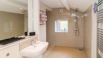 Ein modernes Badezimmer mit großem Spiegel, Waschbecken, Dusche und Fenster.
