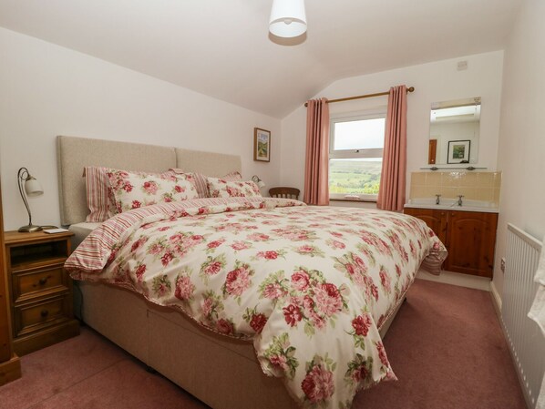 A bedroom with a bed, a nightstand, a dresser, a window with curtains, a mirror, and a radiator. - Barn House (Leyburn)
