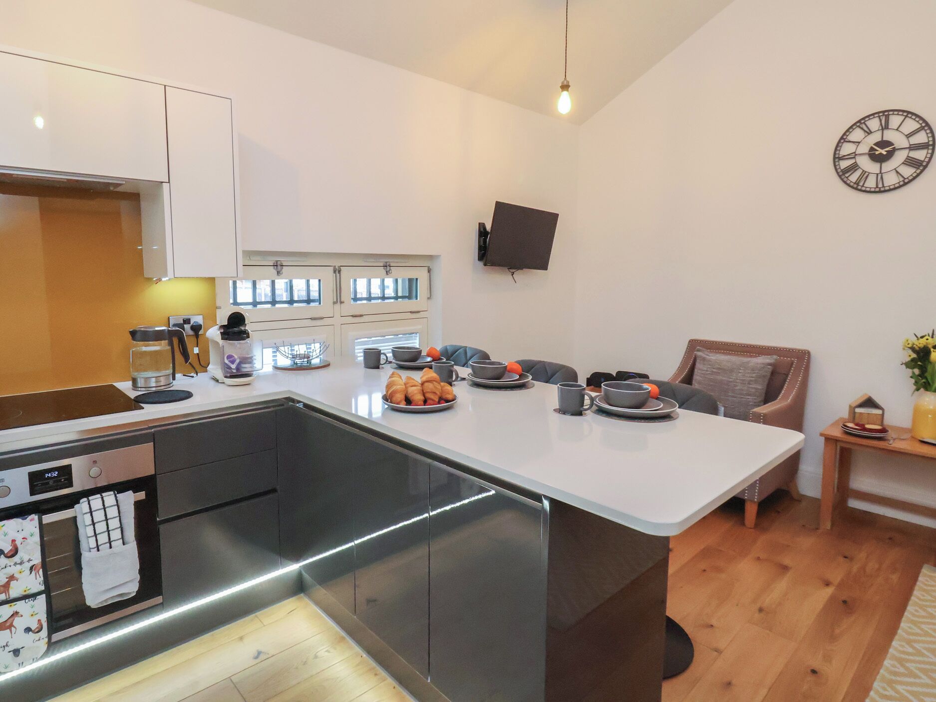Een moderne keuken met een centraal eiland, ingebouwde apparatuur en een eethoek met een stoel en tafel.