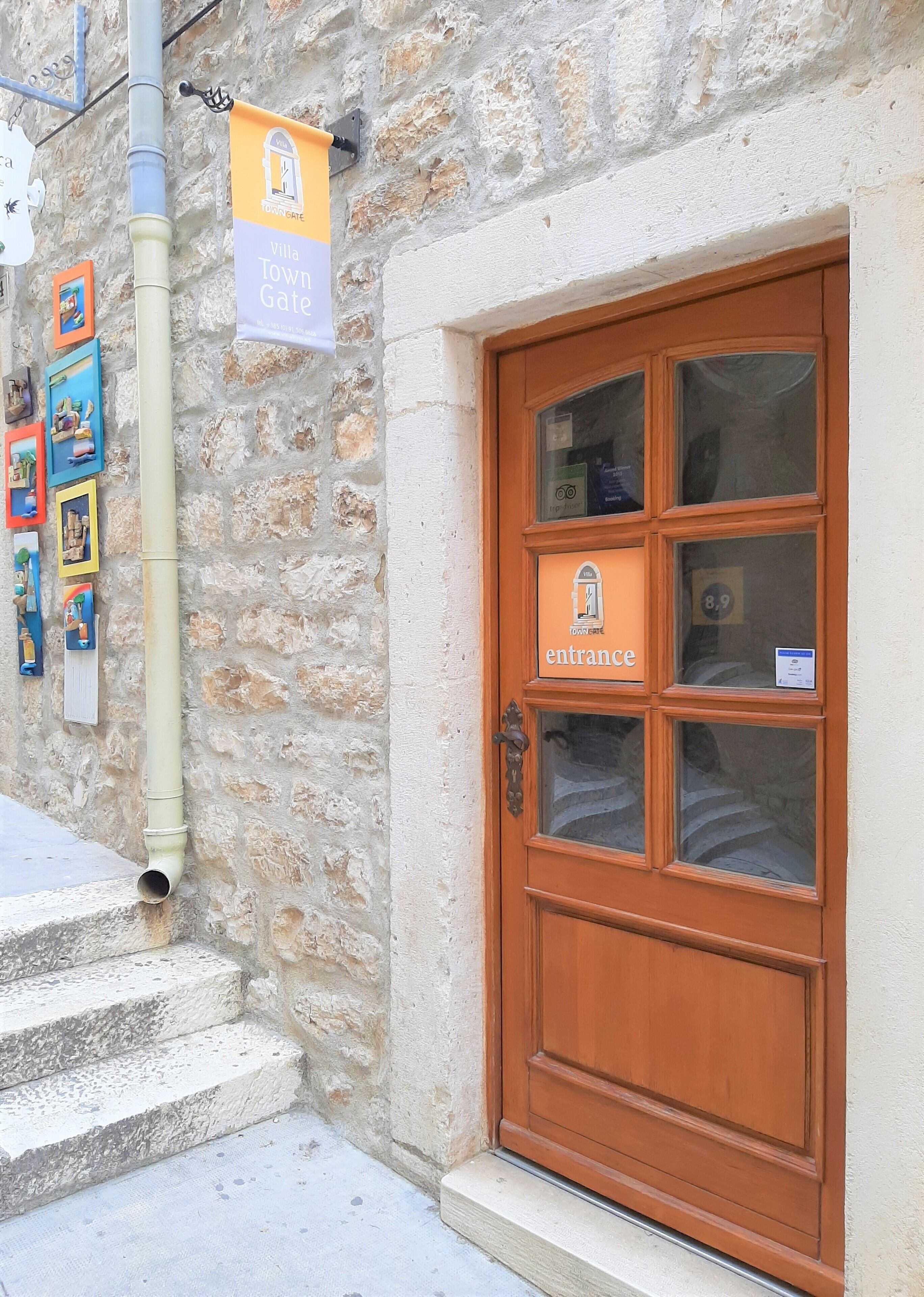 A wooden door with a sign reading "Villa Town Gate entrance" and a number "8.9" on the window.