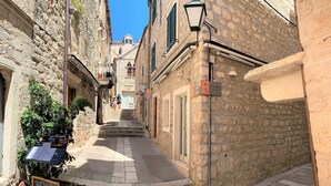 A narrow street with stone buildings, a sign for Villa Town Gate, and a restaurant named Roof Top Dining.