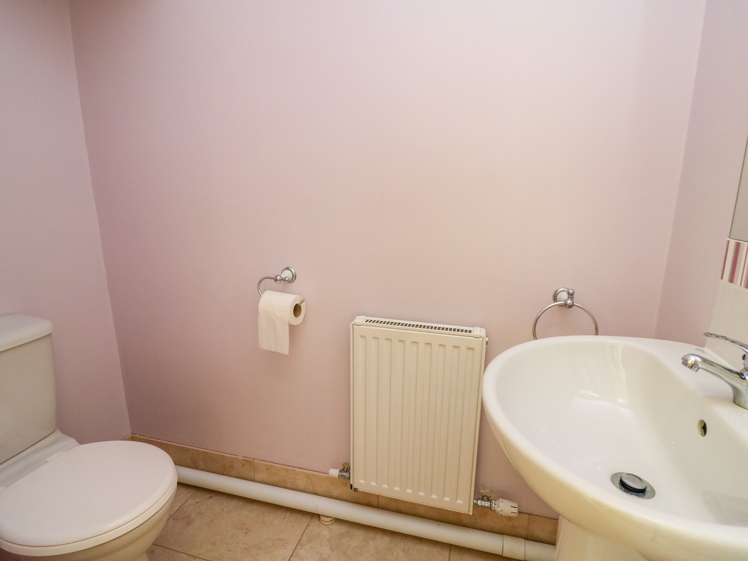 Une salle de bain avec des toilettes, un radiateur et un lavabo.