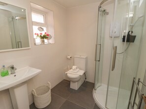 A bathroom with a glass-enclosed shower, a toilet, and a sink. - Arden House (Whitby)
