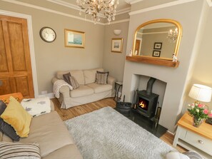 A cozy living room with a sofa, a fireplace, a mirror, and a clock on the wall. - Arden House (Whitby)