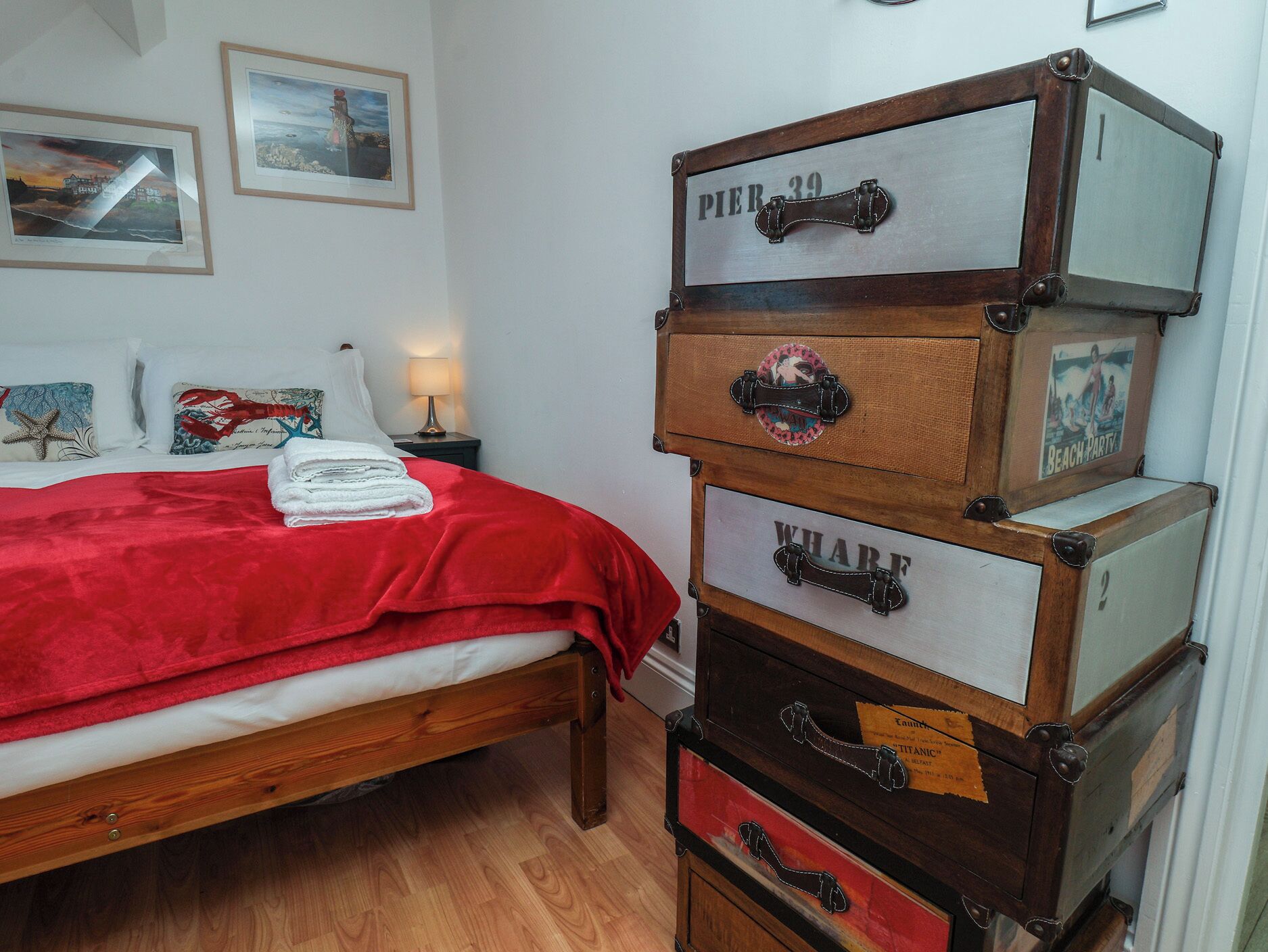 A bedroom with a bed, a dresser with multiple drawers, a nightstand, and wall art.