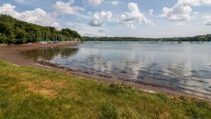 A beach with boats, a grassy area, and a forested hill. - The Tallet (Dartmouth)