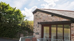 A stone building with a sign reading "THE TAILLET" and a wooden chair on the porch. - The Tallet (Dartmouth)