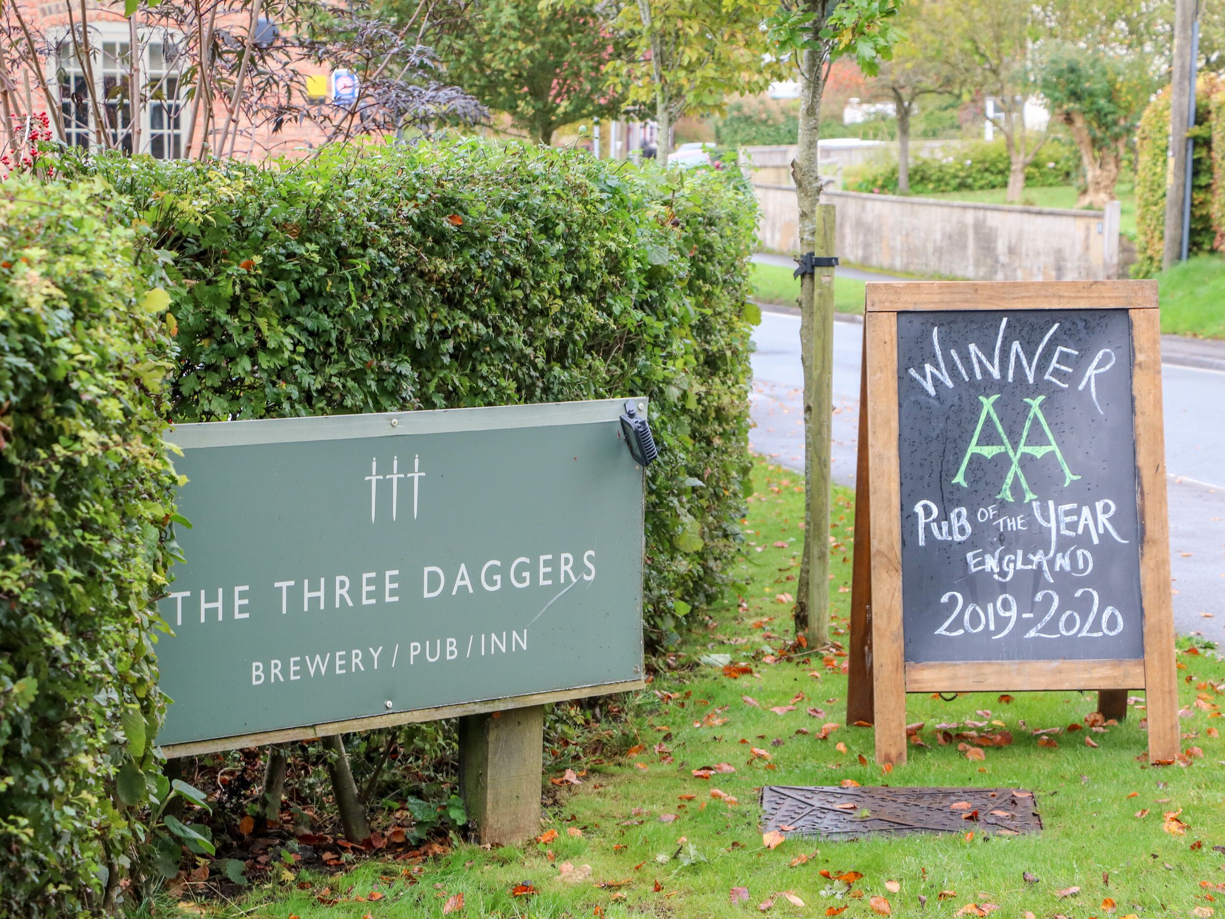 A sign for 'The Three Daggers' brewery and pub, with a chalkboard sign indicating it won 'Pub of the Year' in England for 2019-2020.