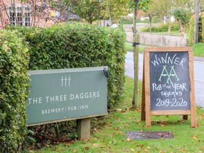 A sign for 'The Three Daggers' brewery and pub, with a chalkboard sign indicating it won 'Pub of the Year' in England for 2019-2020. - Tilly's Cottage (Westbury)