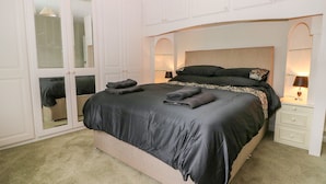 A bedroom with a large bed, a wardrobe with mirrored doors, and two bedside lamps. - Glynde (Dover)