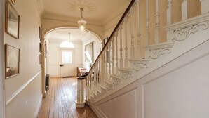 A hallway with wooden flooring, white walls, and a white staircase with ornate balusters. - 12 St Hilda's (Whitby)