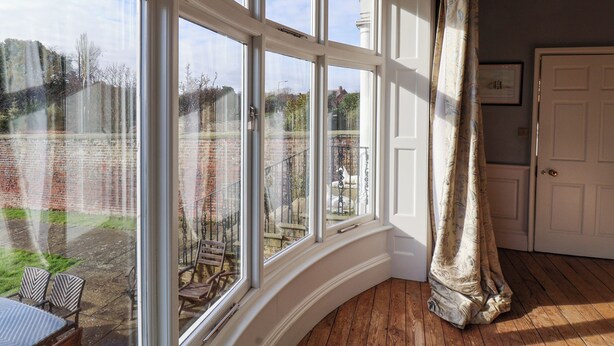 A room with large windows, a wooden floor, a door, and a chair by the window. - 12 St Hilda's (Whitby)