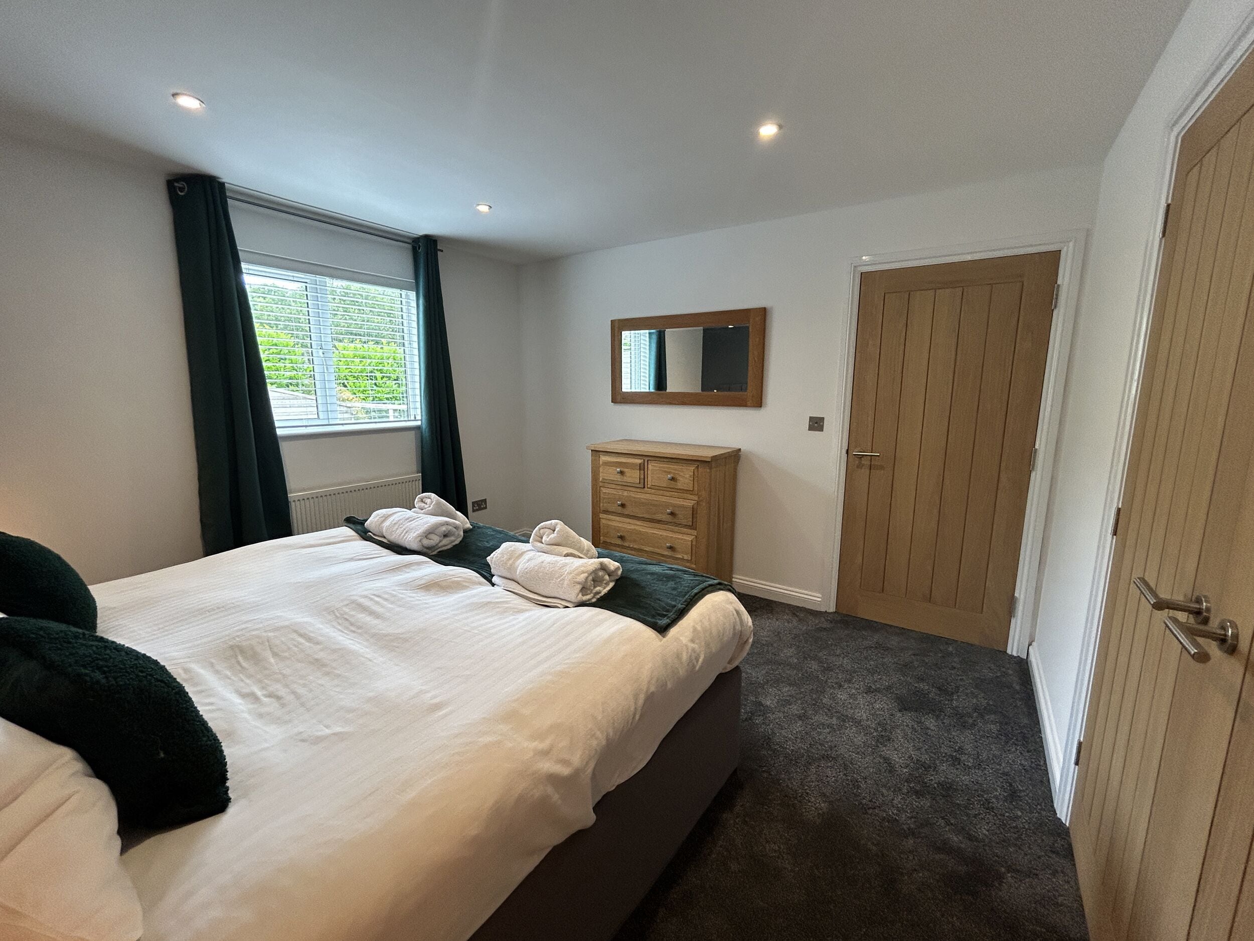 A bedroom with a bed, a dresser, a mirror, and a door.