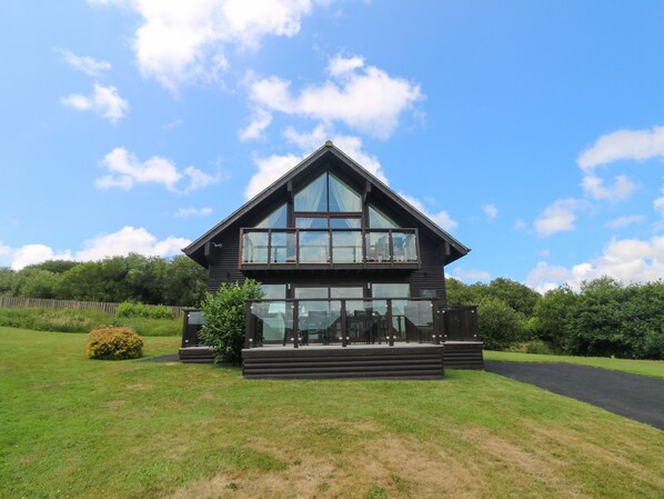 Une maison moderne à deux étages, dotée de grandes fenêtres et d’un balcon.