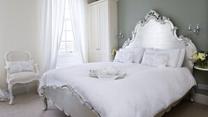 A bedroom with a large bed, white curtains, a white chair, and a white wardrobe. - Albany House, Whitby (Whitby)