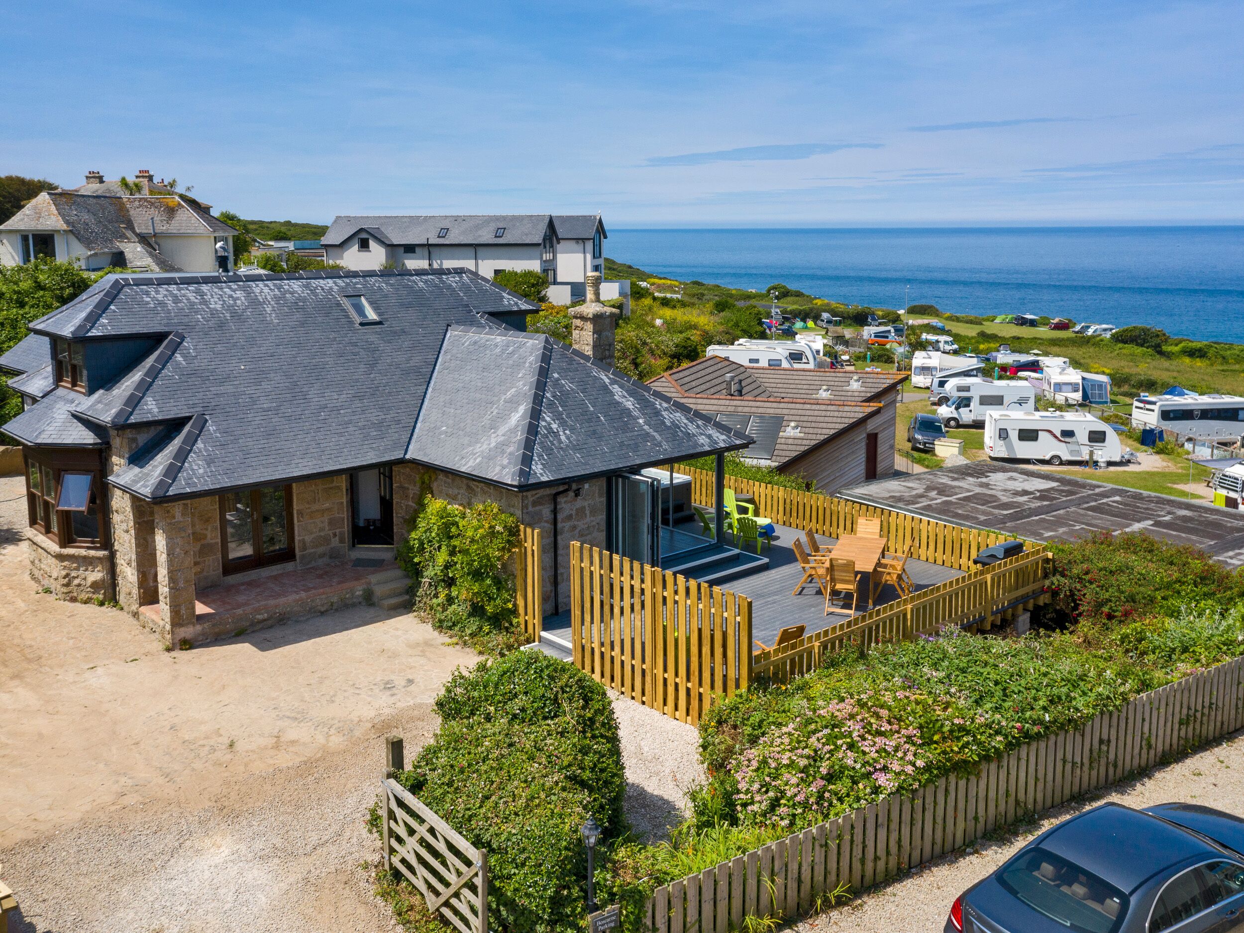 Une propriété située sur la côte, comprenant une grande maison, un espace extérieur aménagé avec un coin salon couvert et une vue sur la mer.
