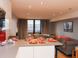 Una sala de estar moderna con comedor, que incluye un juego de sofá, una mesa de centro y una encimera de cocina con alimentos para el desayuno.