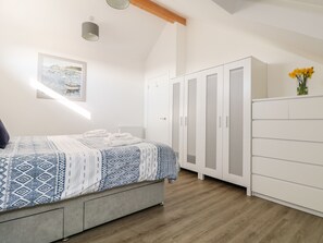 Cozy retreat with a neatly made bed, a spacious wardrobe, and a framed picture above.
