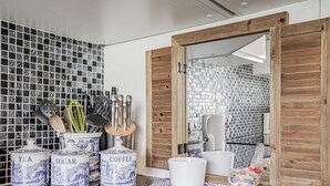 Een keuken met een zwart marmeren aanrecht, een houten deur en een betegelde spatwand.