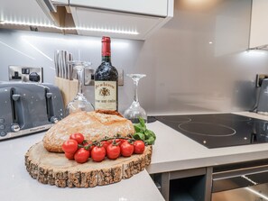 A kitchen counter with a loaf of bread, tomatoes, and a bottle of wine. - George Stephenson @ Engine Shed (Whitby)