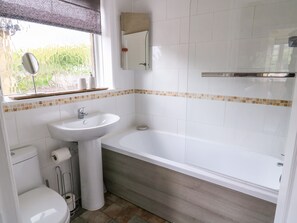 Une salle de bain avec des toilettes, un lavabo et une baignoire.