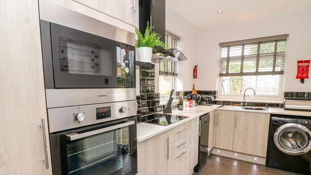 Uma cozinha moderna com forno embutido, máquina de lavar louça, máquina de lavar roupa e pia.