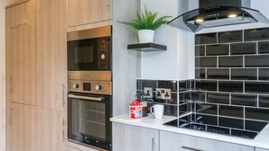 Uma cozinha moderna com forno embutido, micro-ondas e máquina de café no balcão.