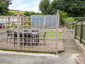 Un espace extérieur clos, agrémenté d’une table et de chaises, et entouré d’une clôture.