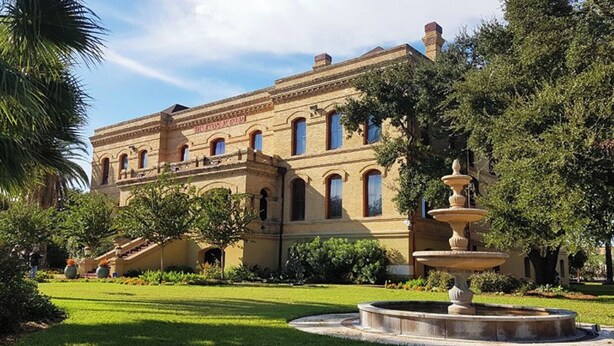 Un edificio histórico con fachada simétrica, ventanas arqueadas y una entrada central.