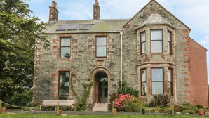 A stone building with a central entrance, multiple windows, and a sloped roof. - Hillcrest (Newton Stewart)