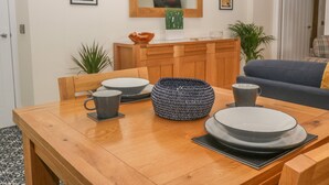 A dining area with a wooden table, plates, a mug, and a patterned bowl. - Hillcrest (Newton Stewart)