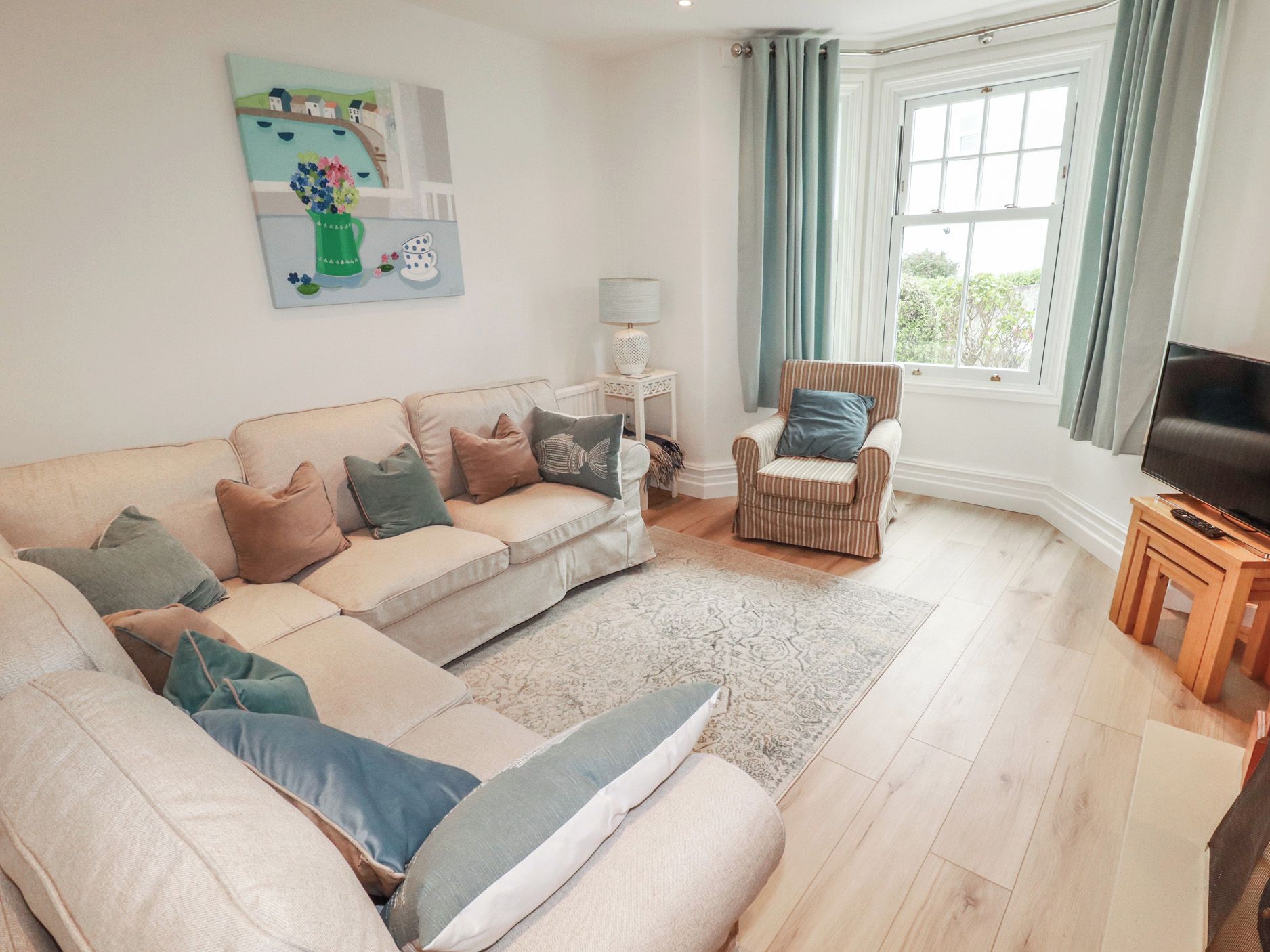 A living room with a sofa, armchairs, a TV, and a painting on the wall.