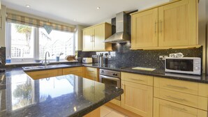 A modern kitchen with a large island, stainless steel appliances, and wooden cabinets. - Beachcomber (Padstow)
