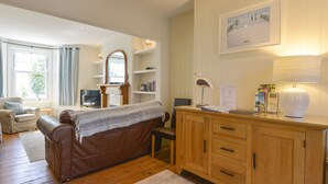 A cozy living room with a brown leather sofa, wooden cabinet, and a framed picture on the wall. - Beachcomber (Padstow)