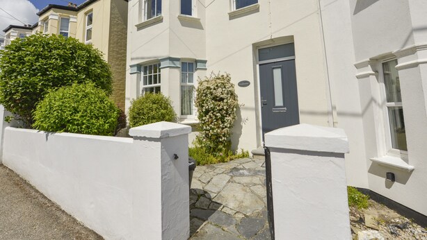 A row of white terraced houses with a stone pathway leading to the front door. - Beachcomber (Padstow)