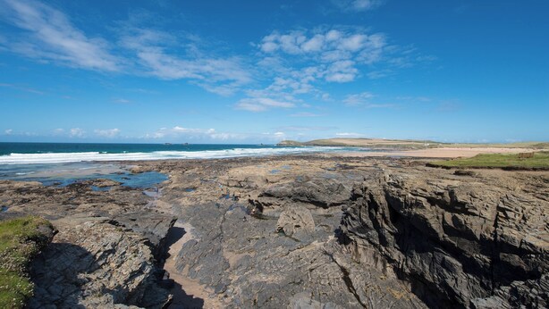 A rocky coastal landscape with a clear sky and ocean in the background. - Beachcomber (Padstow)