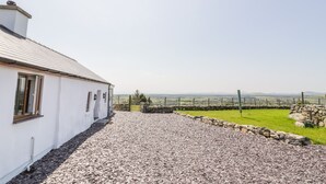 A white building with a gravel driveway leading to a stone wall and a grassy field. - Pen Y Braich Uchaf (Garndolbenmaen)
