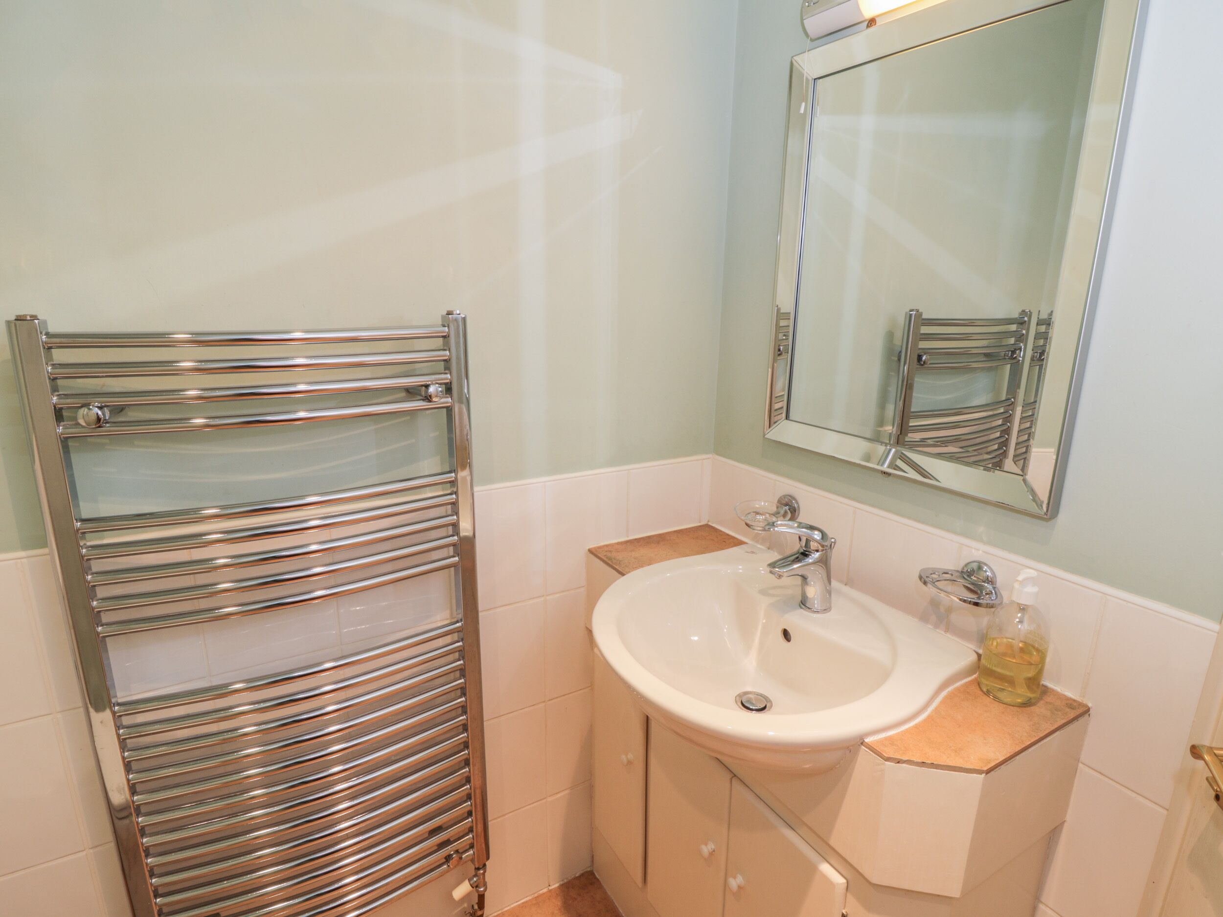 A bathroom with a chrome towel rack, a sink, and a mirror.