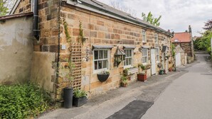 A stone building with multiple windows and a sloped roof. - Old Stables Cottage (Saltburn-by-the-Sea)