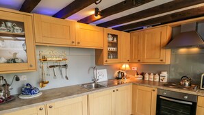 A kitchen with wooden cabinets, a built-in oven, and a stone backsplash. - Old Stables Cottage (Saltburn-by-the-Sea)