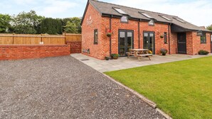 A brick building with a sloped roof, a picnic table, and a wheelchair-accessible entrance. - The Dairy (Tarporley)