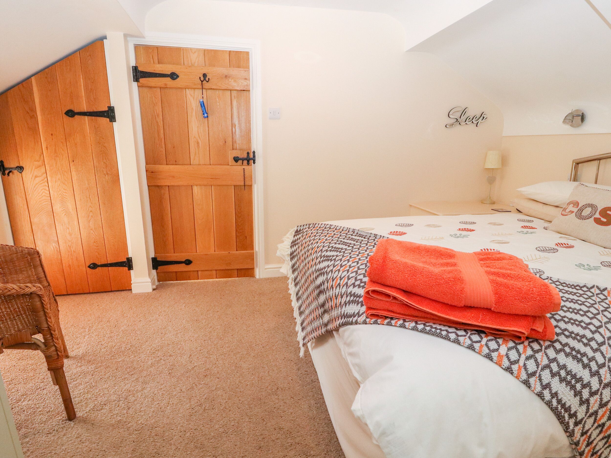 Un dormitorio con puerta de madera, una cama con ropa de cama estampada y una silla.