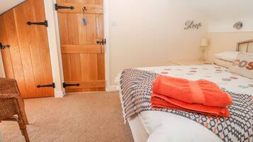 Un dormitorio con puerta de madera, una cama con ropa de cama estampada y una silla.