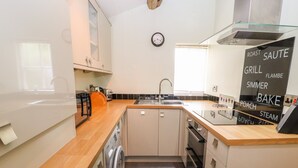 A compact kitchen with a washing machine, a sink, and a stove. - The Dairy (Tarporley)