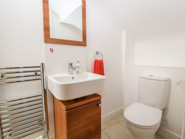 A bathroom with a white sink, a mirror, a toilet, and a towel rack. - The Dairy (Tarporley)