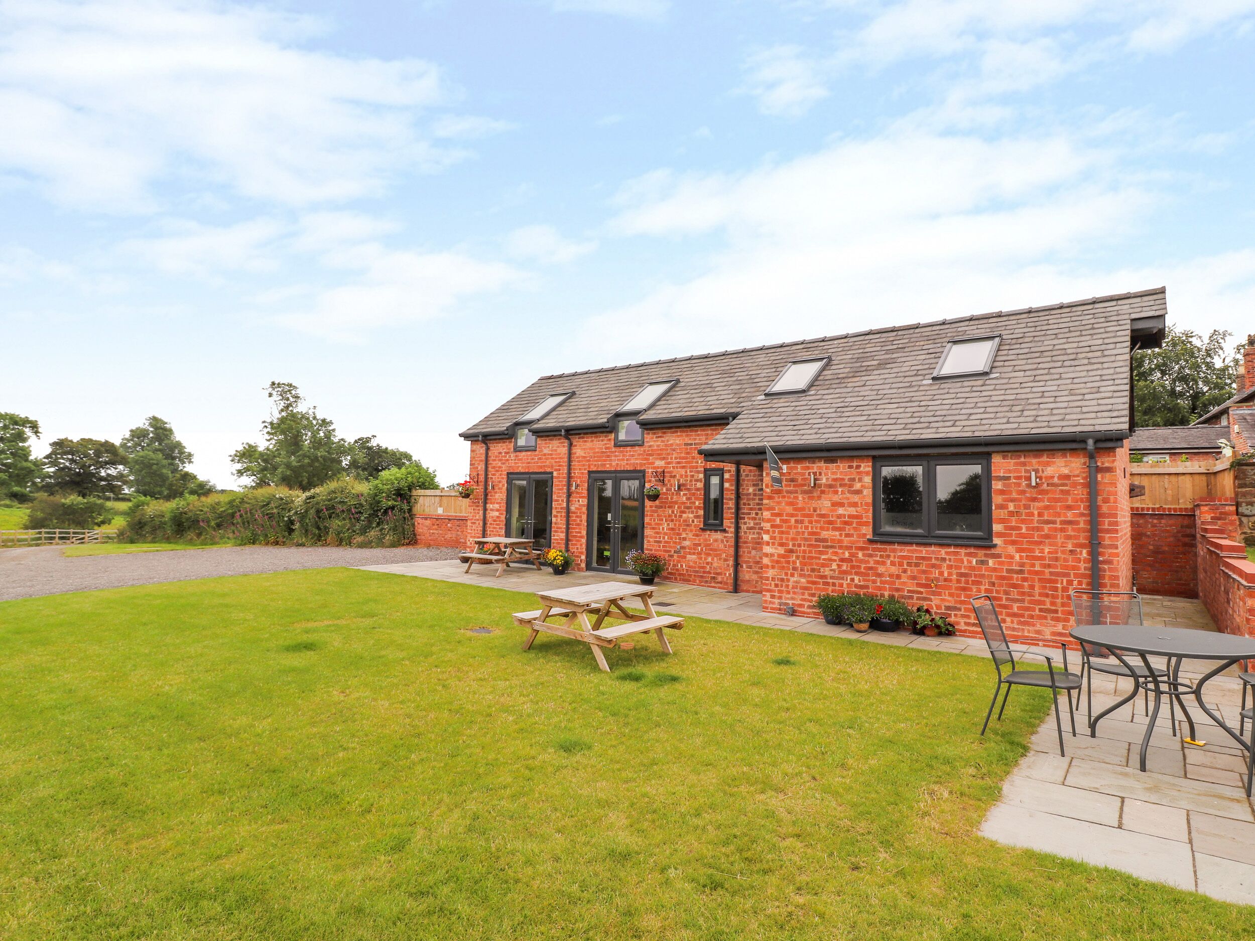 A brick house with a patio, a wooden table, and a garden.
