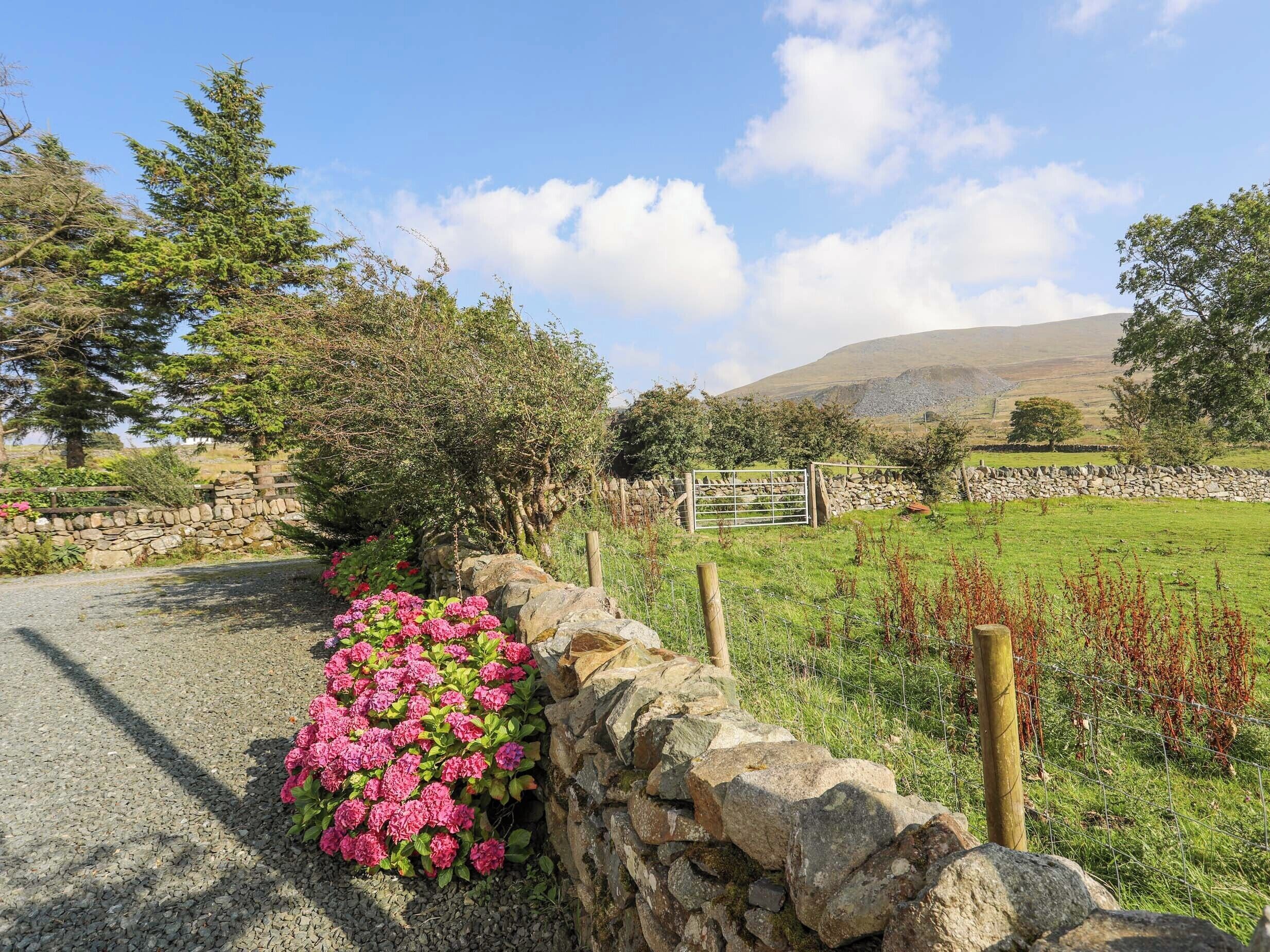 A rural landscape with a stone wall, a gravel path, and a field.