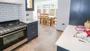 Une cuisine moderne équipée d’une cuisinière à gaz, d’un four et d’un coin repas avec des chaises et une table en bois.