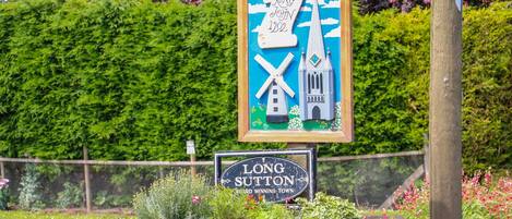 Ein Schild für Long Sutton, Gewinner des Wettbewerbs ‚Beste Marktstadt‘ des C.P.R.E, mit einer Darstellung einer Windmühle und einer Kirche.